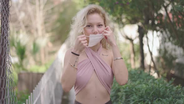 Close-up portrait of nice-looking, beautiful, sexy woman putting on surgical protective mask alt