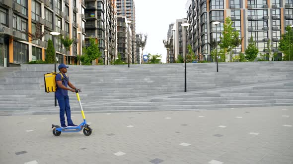 Afroamerican Man Courier Delivery with Backpack Rides Street Electric Scooter alt