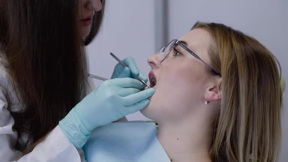 Female Dentist in Medical Gloves Scaling with Tools Patient's Teeth in Clinic alt