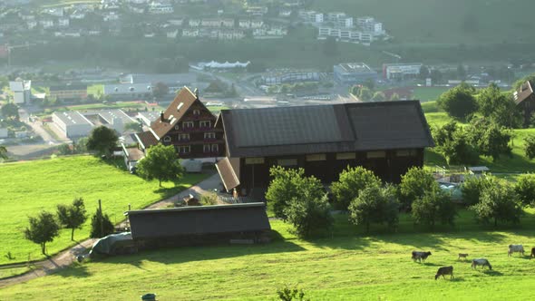 Lonely Farm on the Background of a Modern Urban Settlement in the Swiss Alps.