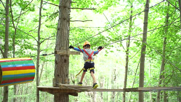Little Boy Walks Across the Agility Bridge in Adventure Park alt