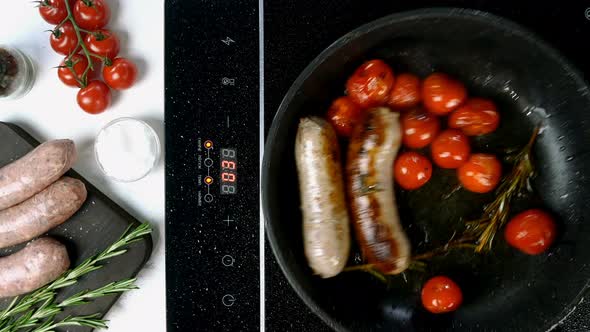 Fatty White Bavarian Sausages with Tomato and Sprig of Rosemary Fried in Frying Pan alt