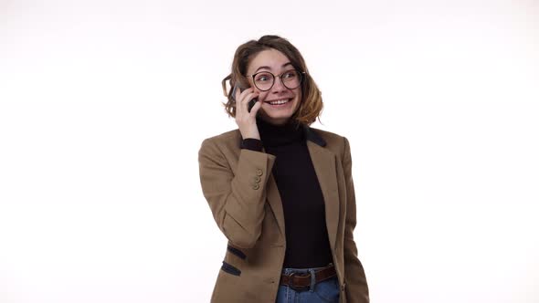 European Stylish Young Woman Receiving Good News While Talking on Mobile Phone Isolated Over White alt