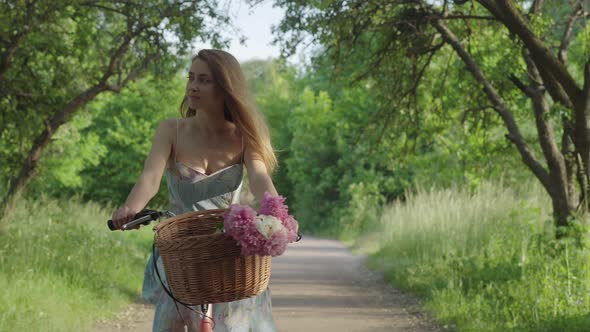 Confident Young Brunette Woman Riding Bicycle Along the Alley in Sunny Summer Park. Portrait of alt