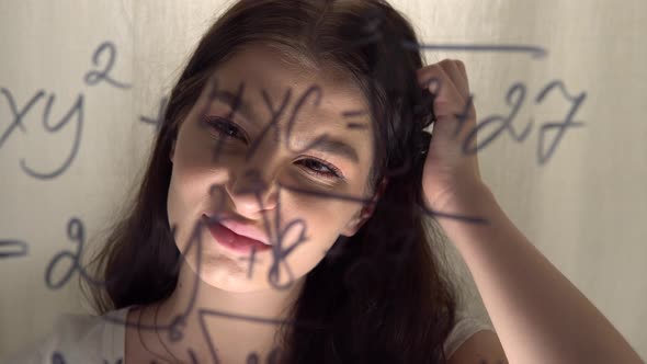 Woman Student Looking at Equation on Glass Whiteboard Thinking Scratching Head