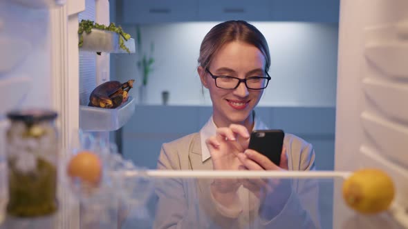 Hungry woman opening fridge looking inside searching for food. Online ordering food delivery.