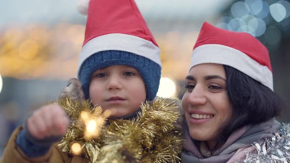Closeup Slim Beautiful Woman and Cute Little Boy Admiring Christmas Sparklers Enjoying New Year Day alt