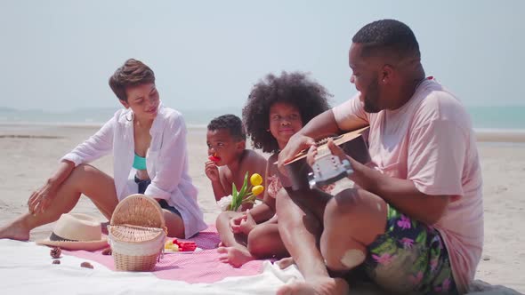 Parents and two children are relaxing together on the beach. alt