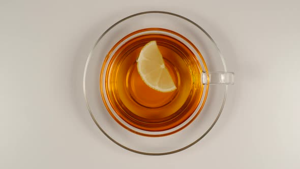 Lemon Slice Swims In A Black Tea In A Glass Tea Cup With A Dish alt