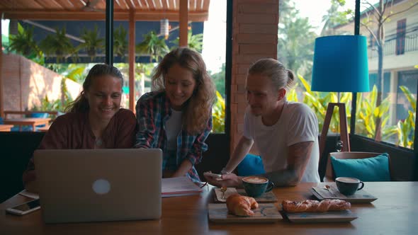 Team of Young Coworkers Working on Laptops and Discussing Business alt