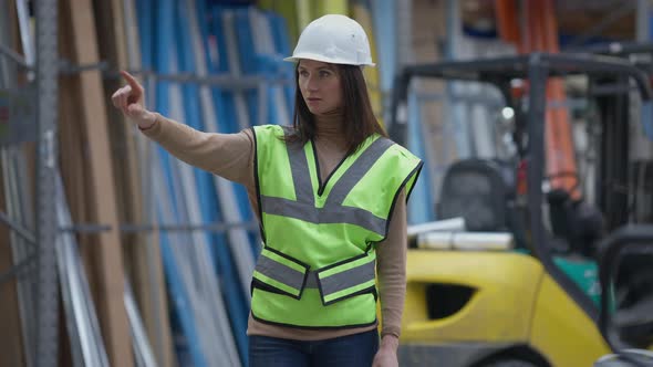 Concentrated Professional Female Warehouse Worker in Hard Hat Touching Invisible Cyber Screen in alt