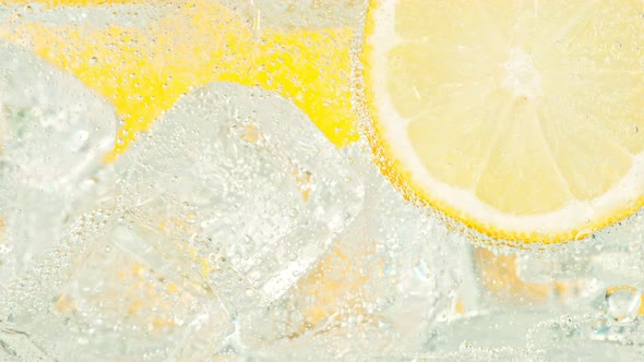 Super Slow Motion Shot of Fizzing Water with Lemon Slices and Ice Cubes in Glass at 1000 Fps alt