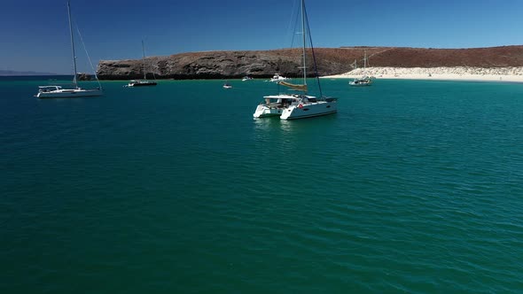 Boats Adrift Off The White Sand Shoreline Of Playa Balandra In La Paz, Mexico. panning right alt