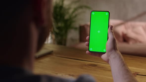 Handheld Camera Young Man at Home Holding Chroma Key Green Screen Smartphone Watching Content alt