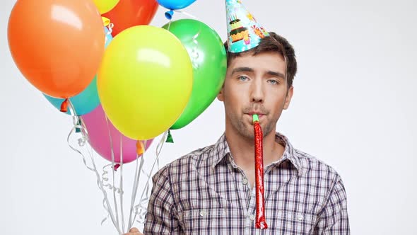 Young Caucasian Male with Dark Hair and Light Bristle on White Background Wearing Birthday Cap Sadly alt