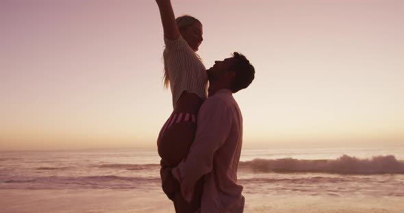 Caucasian couple enjoying time at the beach during the sunset alt