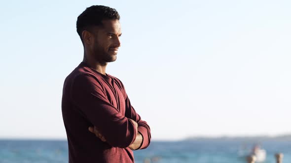 Handsome and Confident Outdoor Portrait of Relaxing Young African Man Traveler on the Beach alt