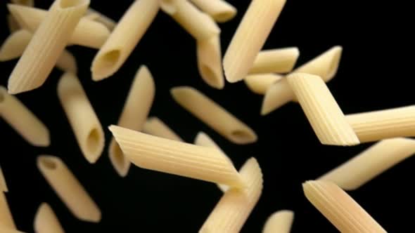 Closeup of the Pasta Penne Falling Down on a Black Background alt