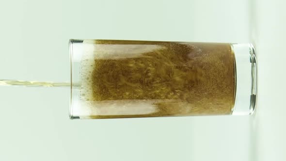 Vertical Video Cola is Poured Into Glass Full of Bubbles and Foam Isolated on White Background