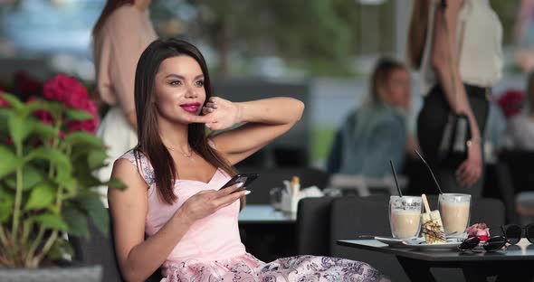 Lovely Girl Drinks Coffee in the Summer Cafe and Wait Someone