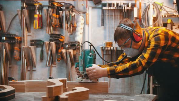 Carpentry Indoors - a Man Woodworker Polishes the Plank alt