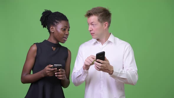 Two Young Multiethnic Business Couple Using Phone Together