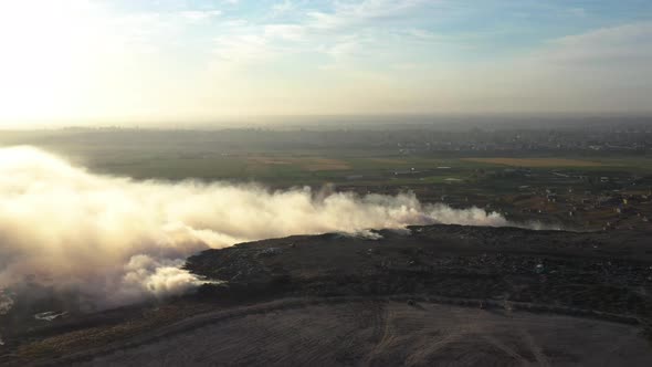 Aerial view of burning garbage pile in trash dump or landfill alt