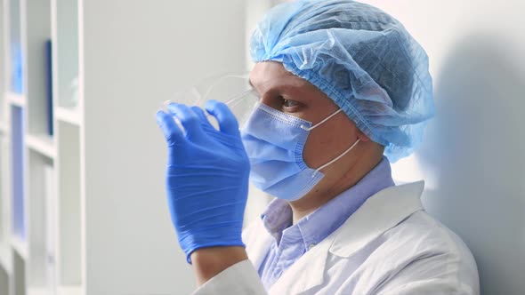 The Doctor Takes Off His Glasses. The Medic Takes Off His Glasses And Medical Cap With His Hands alt