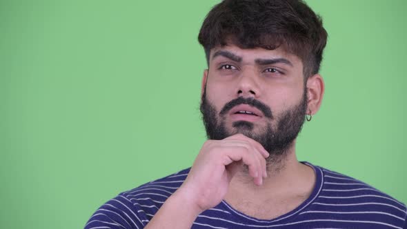 Face of Happy Young Overweight Bearded Indian Man Thinking alt