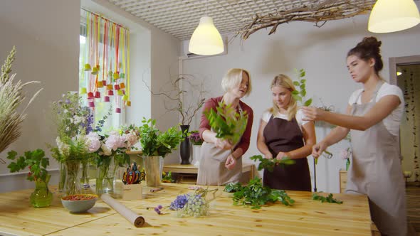 Experienced female florist instructing two trainees alt