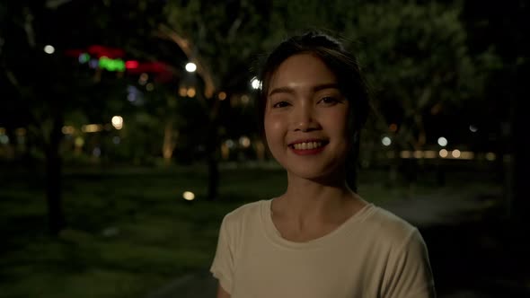 girl relax walk on footpath and cheerful smile looking at camera around tree in park. alt