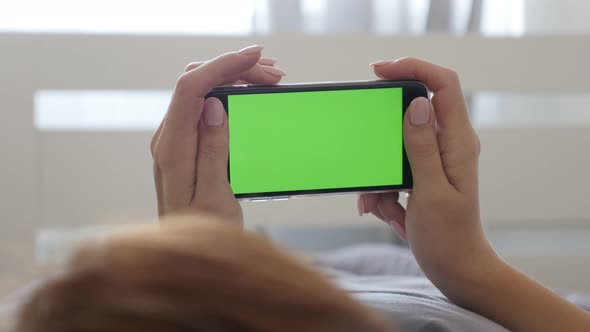 Woman in hands holds green screen display smart phone 4K 2160p 30fps UltraHD footage - Female in bed