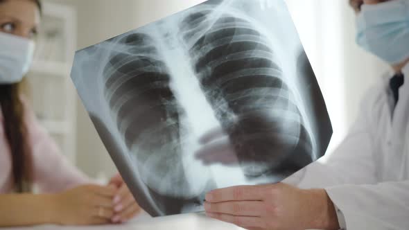 Close-up Lungs X-ray with Doctor and Patient in Face Masks Talking at the Background. Physician alt