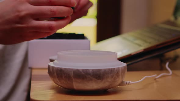 Woman Adds Essential Oil Into Diffuser alt