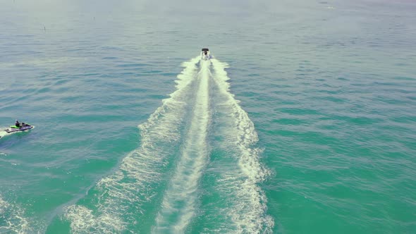 Speed Motor Boat Sailing on Blue Sea Water Leaving White Swirl Trails Behind at Summer alt