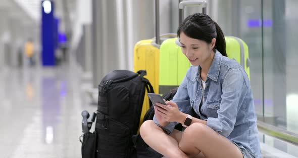 Woman feeling bored and waiting for flight in airport with her luggage and backpack alt