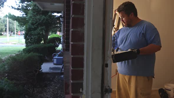 Home Renovation in the Handyman Paints with a Paint Brush a Window Molding Frame alt