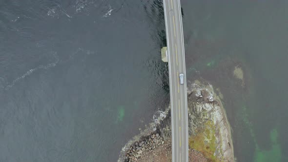 View Of Vehicle Crossing Storseisund Bridge in Atlantic Ocean Road, Norway. - Drone shot, top down alt
