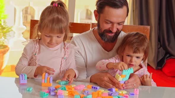 Father Plays Constructor Game with His Two Daughters at Home