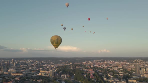 Hot air balloons fly over the summer city.