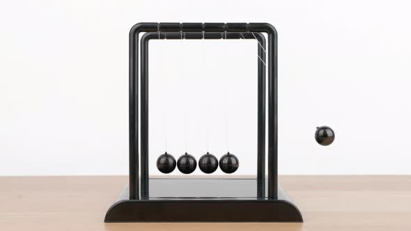 Newton's Cradle metal balls on wooden desk, swinging metal balls, Close up.