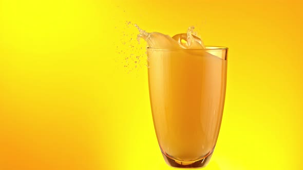 Super Slow Motion Shot of Ice Cubes Falling Into Glass of Orange Juice and Making Splash at 1000Fps alt