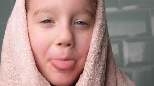 Portrait of Cheerful Little Girl Wrapped in Bath Towel and Looking in Camera