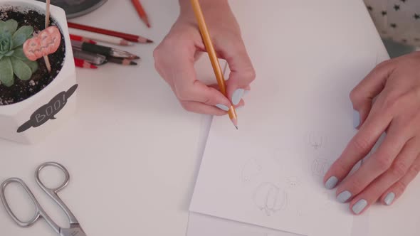 Woman Draws Pumpkin and Ghosts. Handmade Decorations for Halloween. DIY Boo Stickers for Flower Pots