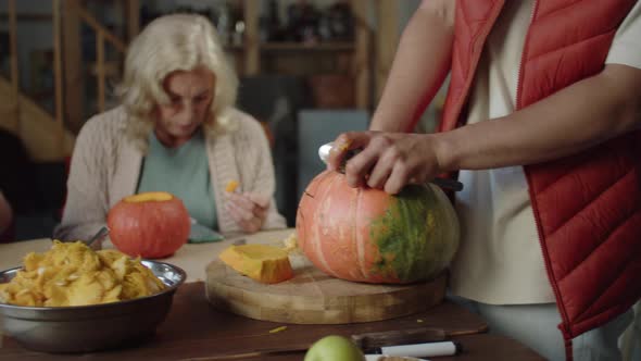 Family Sitting at the Table and Taking Out the Pulp From the Pumpkin and Carving the Lamps for alt
