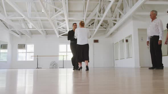 mixed race male dance teacher taking a ballroom dancing class at a dance studio alt