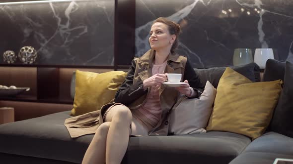 Portrait of Confident Caucasian Slim Woman Sitting on Comfortable Couch in Furniture Showroom alt