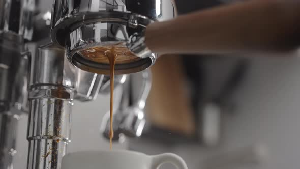 Slow Motion Low Angle Shot of Coffee Extraction with Naked Portafilter Into White Cup alt