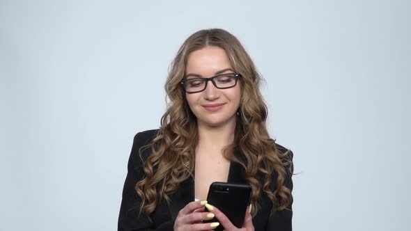 Pretty Girl Makes Selfie on Mobile Phone on Gray Background at Studio, Slow Motion alt