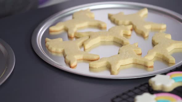 Step by step. Decorating unicorn sugar cookies with royal icing on baking sheet alt